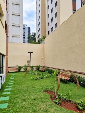 A courtyard with a grassy area, benches, and a pathway. - New Listing (São Paulo)
