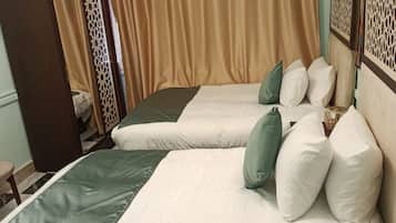 A hotel room with two beds, beige curtains, and an air conditioning unit on the wall.