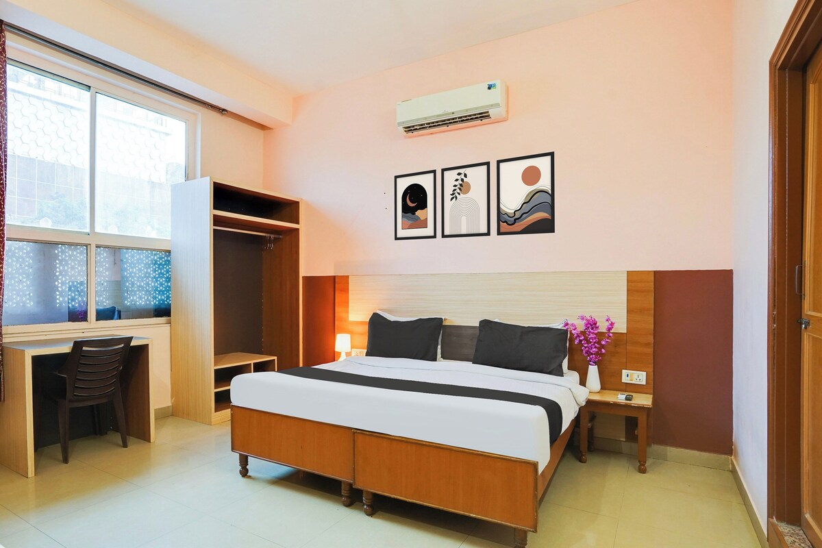 Een hotelkamer met een bed, bureau en kledingkast. Drie ingelijste kunstwerken hangen aan de muur.