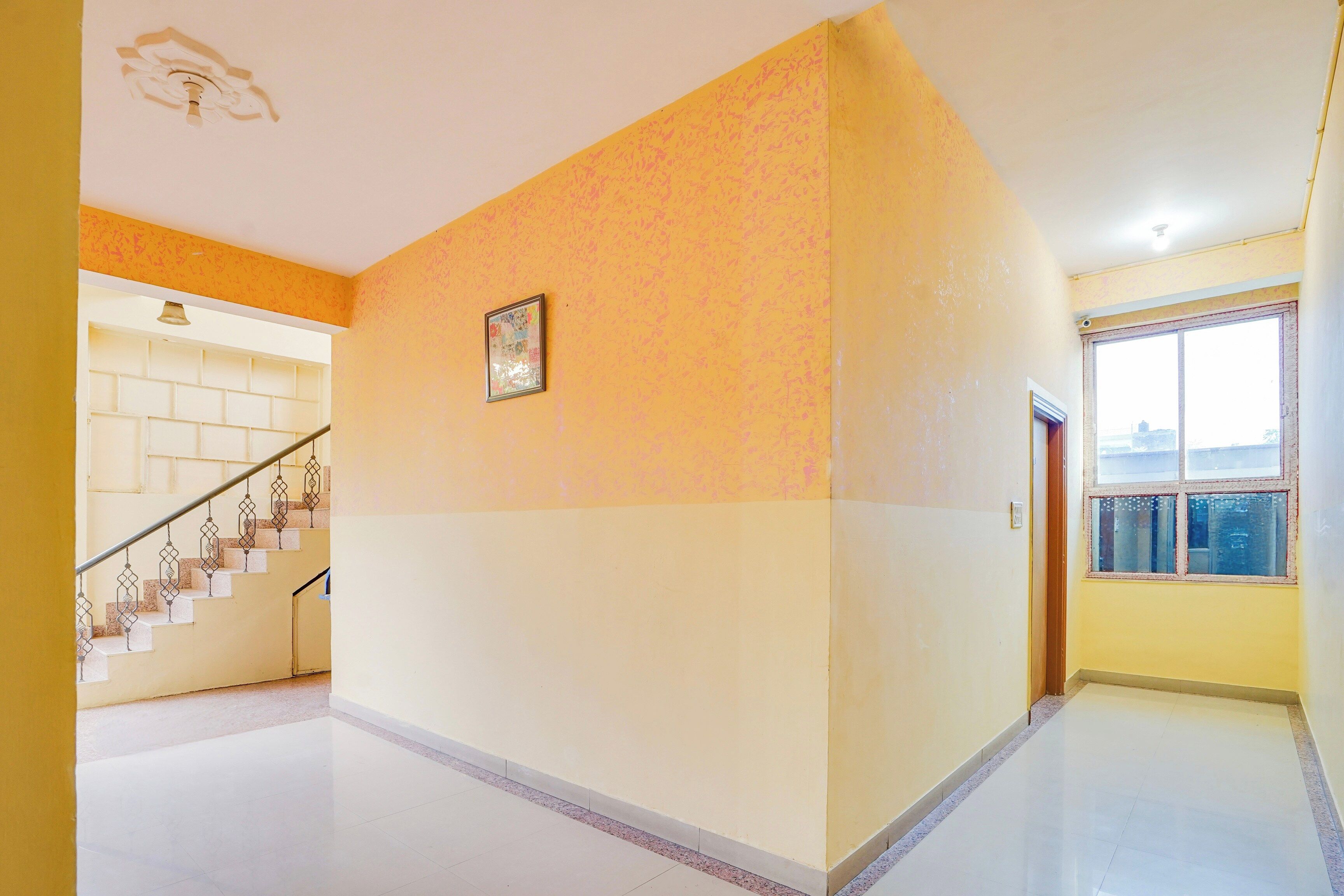Un pasillo con una escalera, un cuadro en la pared y una ventana con vistas.