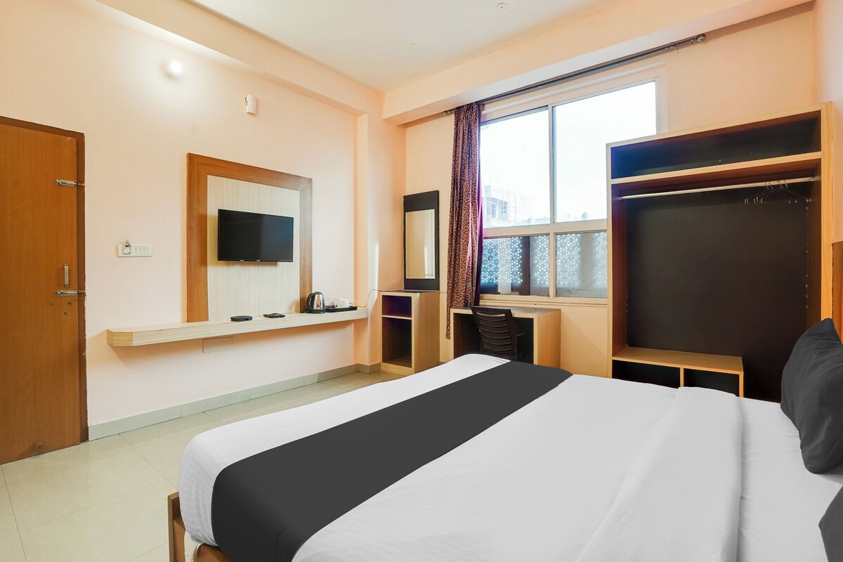 Ein Hotelzimmer mit Bett, Wandfernseher, Schreibtisch mit Stuhl und Kleiderschrank.