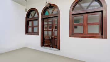 Three arched wooden windows with glass panes, a white ceiling, and a plain wall.