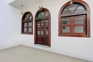 Three arched wooden windows with glass panes, a white ceiling, and a plain wall. - Collection O Khajuraho Central (Khajuraho)