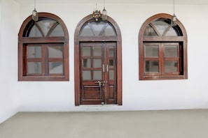 Tres ventanas arqueadas con marcos de madera y vidrios, instaladas en una pared lisa.