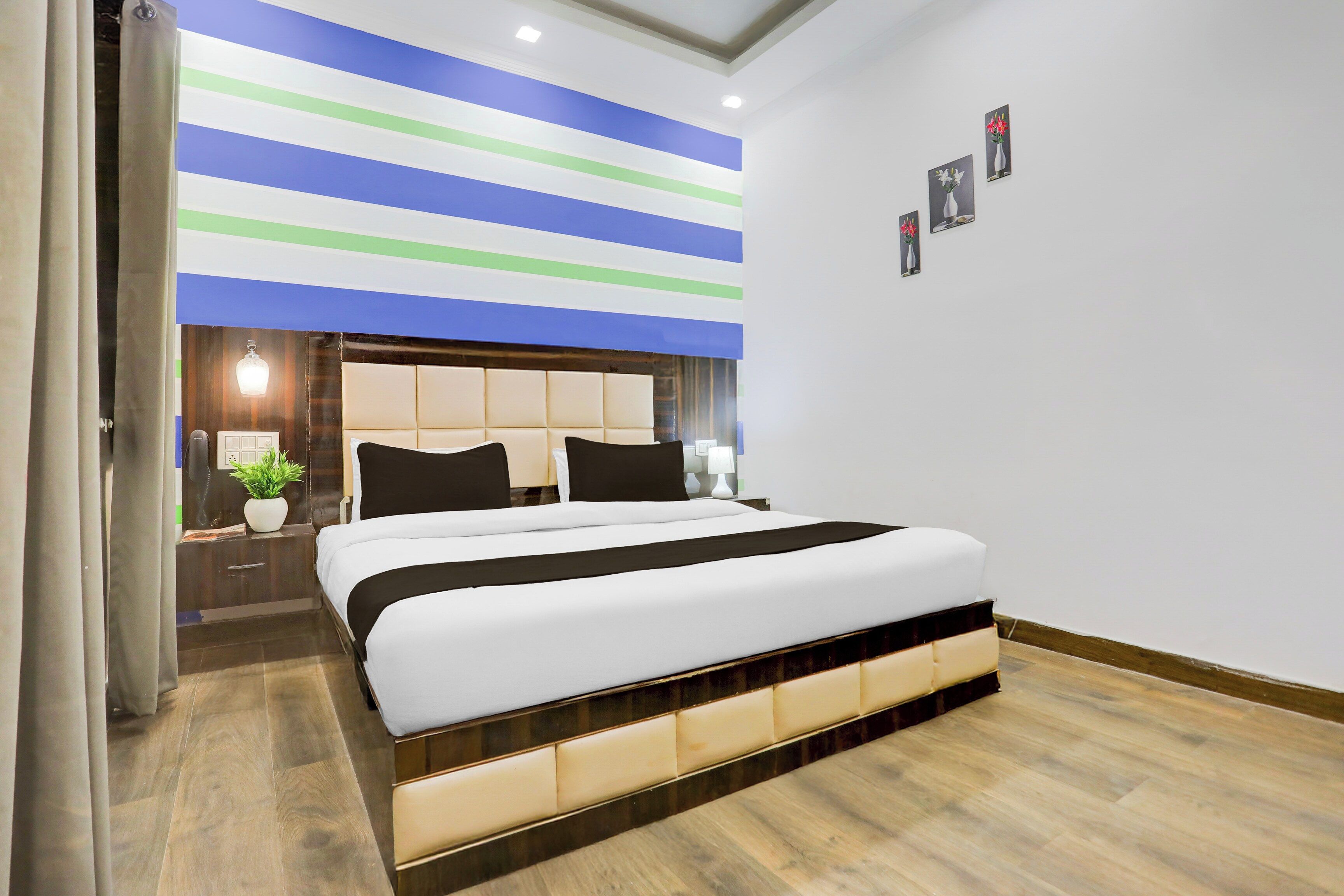 A modern bedroom with a large bed, a nightstand, a bedside table, and a wall-mounted light fixture.