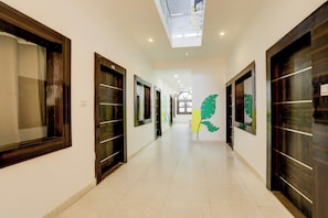A hallway with doors, a clock, and a green leaf decoration. - Collection O Khajuraho Central (Khajuraho)