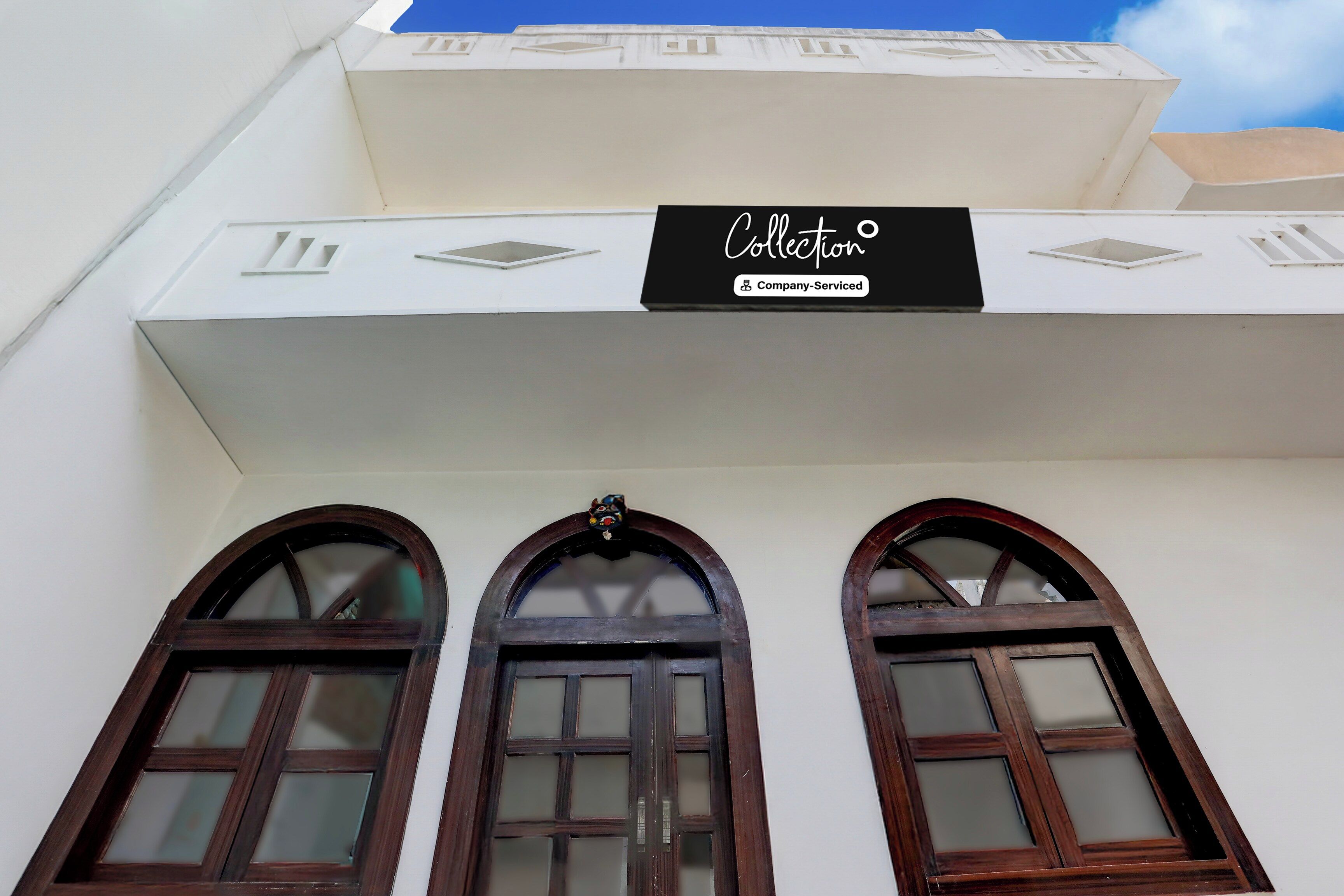 A building with a sign that reads 'Collection Company-Serviced' above three arched windows.