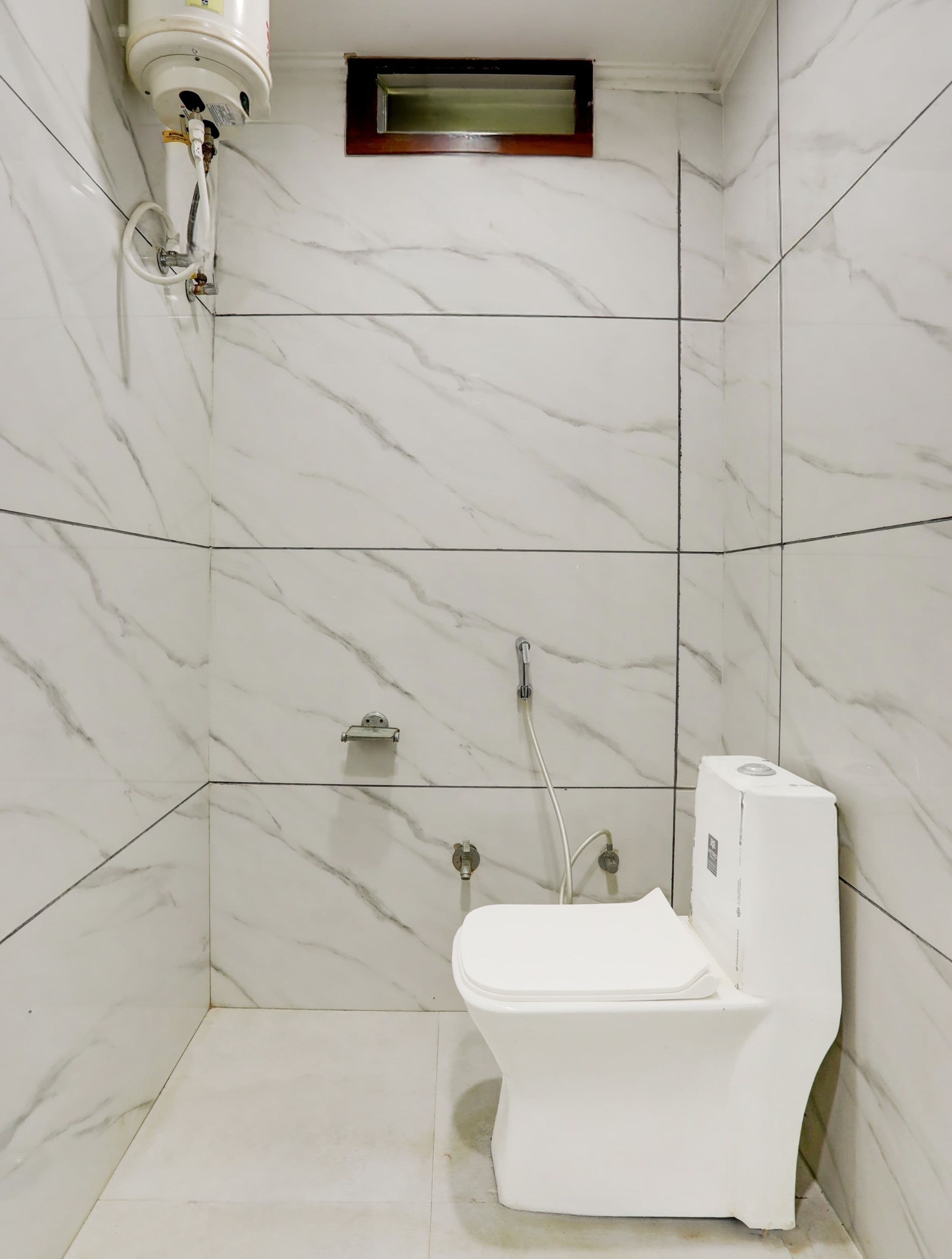 A bathroom with a toilet, a shower, and a built-in water heater.