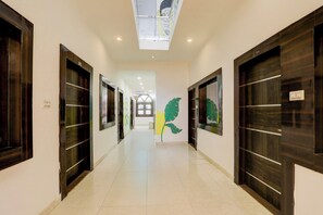Un pasillo con puertas de madera oscura, paredes blancas y un techo con tragaluces.