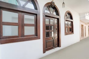 A corridor with arched windows and a door, featuring a simple, clean design with white walls and wooden frames. - Collection O Khajuraho Central (Khajuraho)