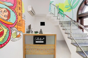Una escalera con barandilla de vidrio y una pared con un mural colorido.