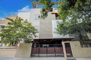 Un edificio moderno de varios pisos con una escalera central, rodeado de vegetación.