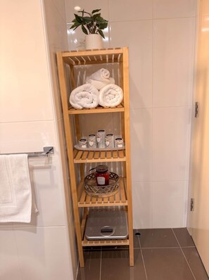 A wooden shelf unit with towels, jars, and a scale in a bathroom. - Braddon Luxe Retreat ,Parking, Gym & City Views (Braddon)
