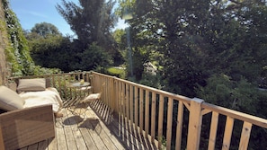Eine Holzterrasse mit Korbmöbeln und einem kleinen runden Tisch.