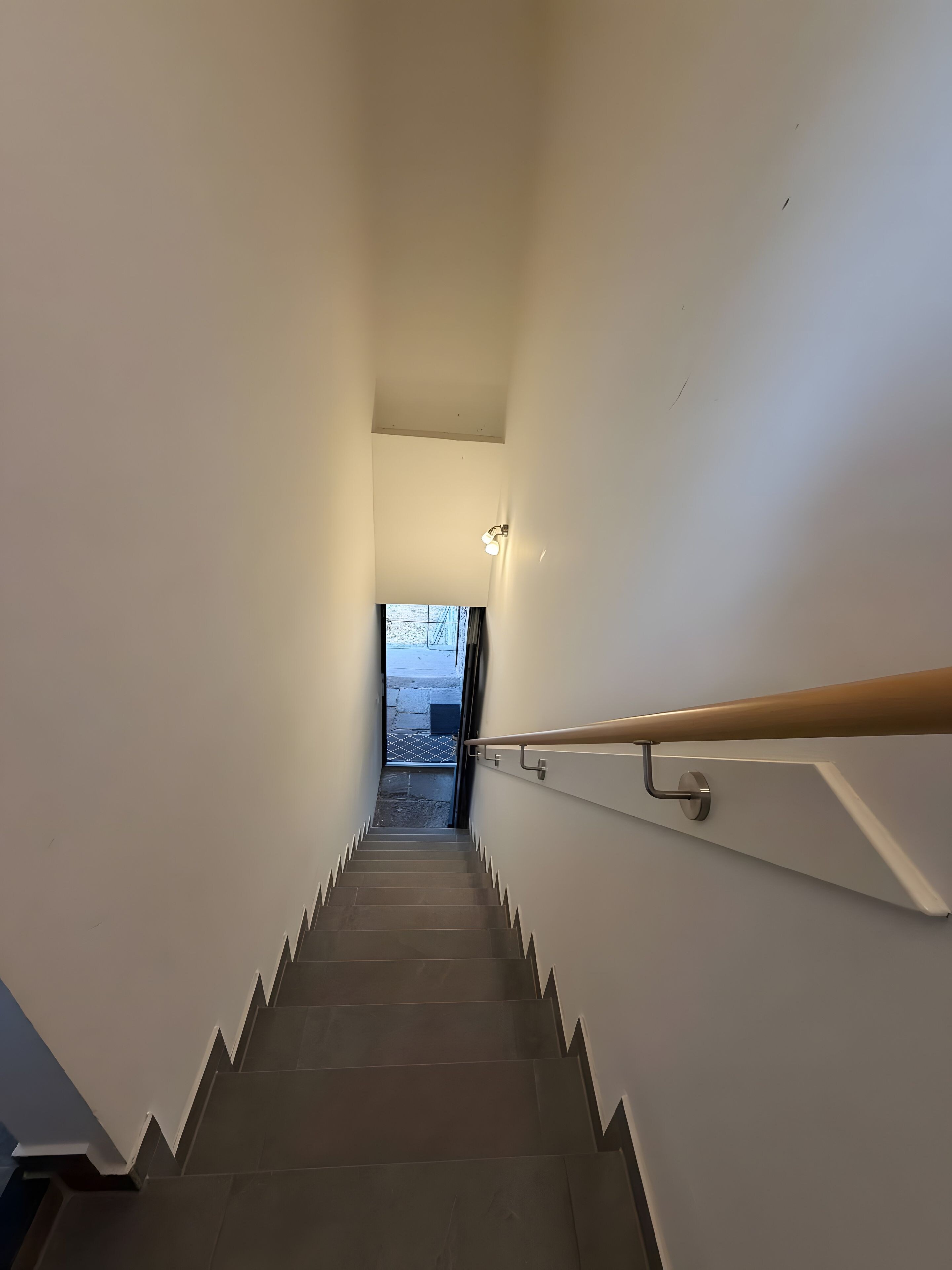 Una escalera con barandilla y una lámpara en la pared.