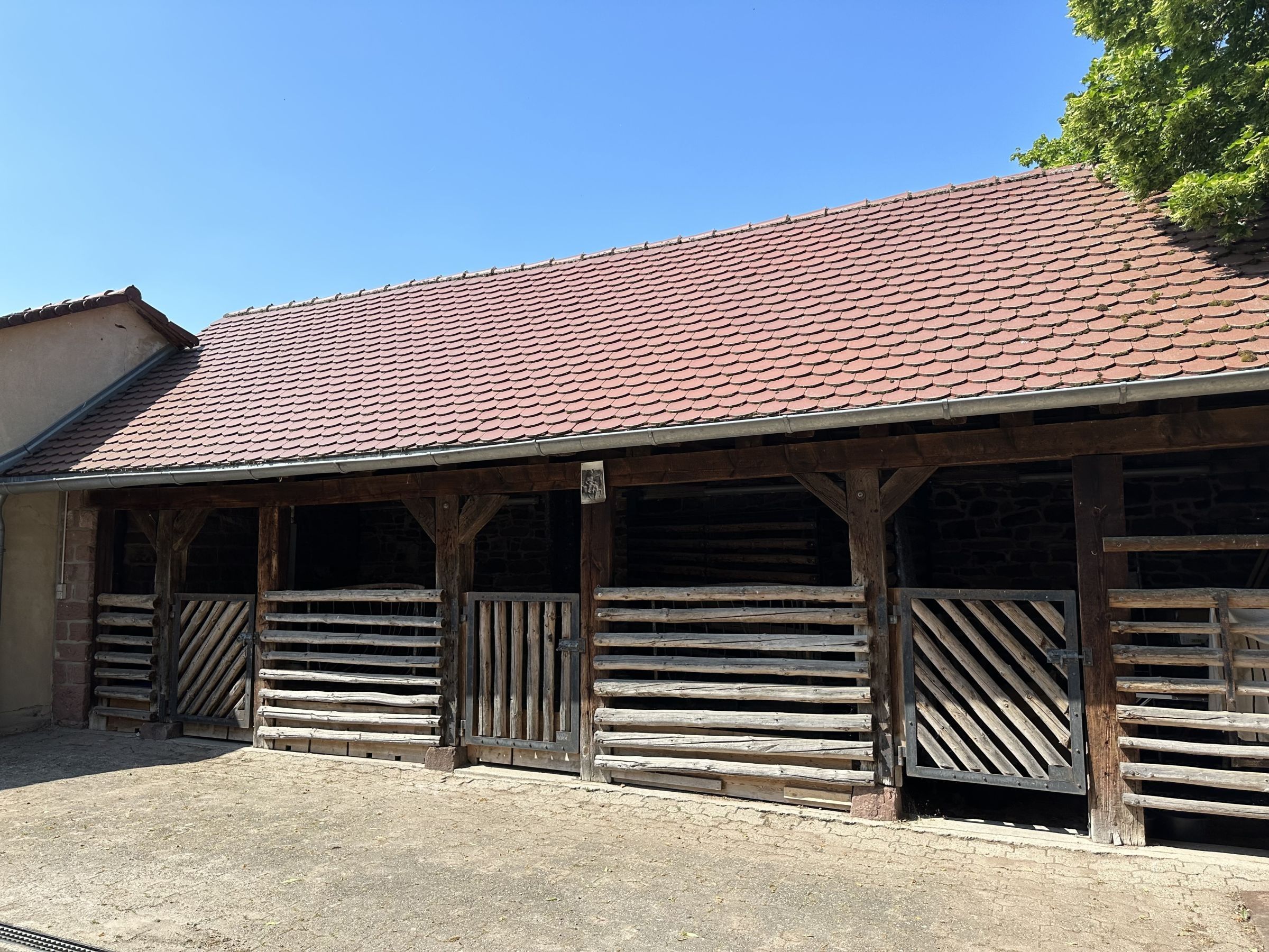 Un bâtiment rustique avec un toit en tuiles et une structure en bois.