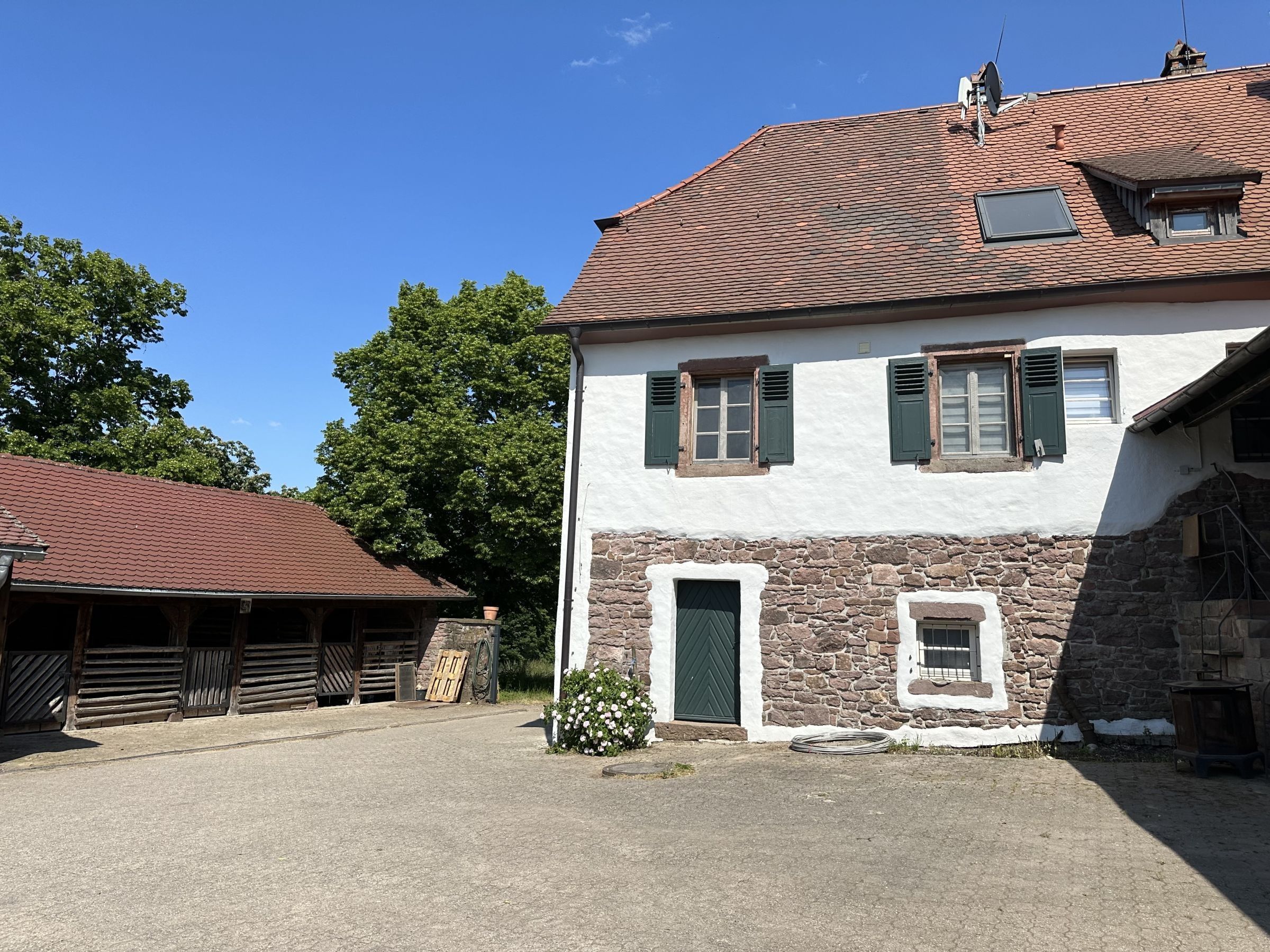 Ein zweistöckiges Gebäude mit einer steinernen Fassade, einem Ziegeldach und einem kleinen Fenster mit Fensterläden.