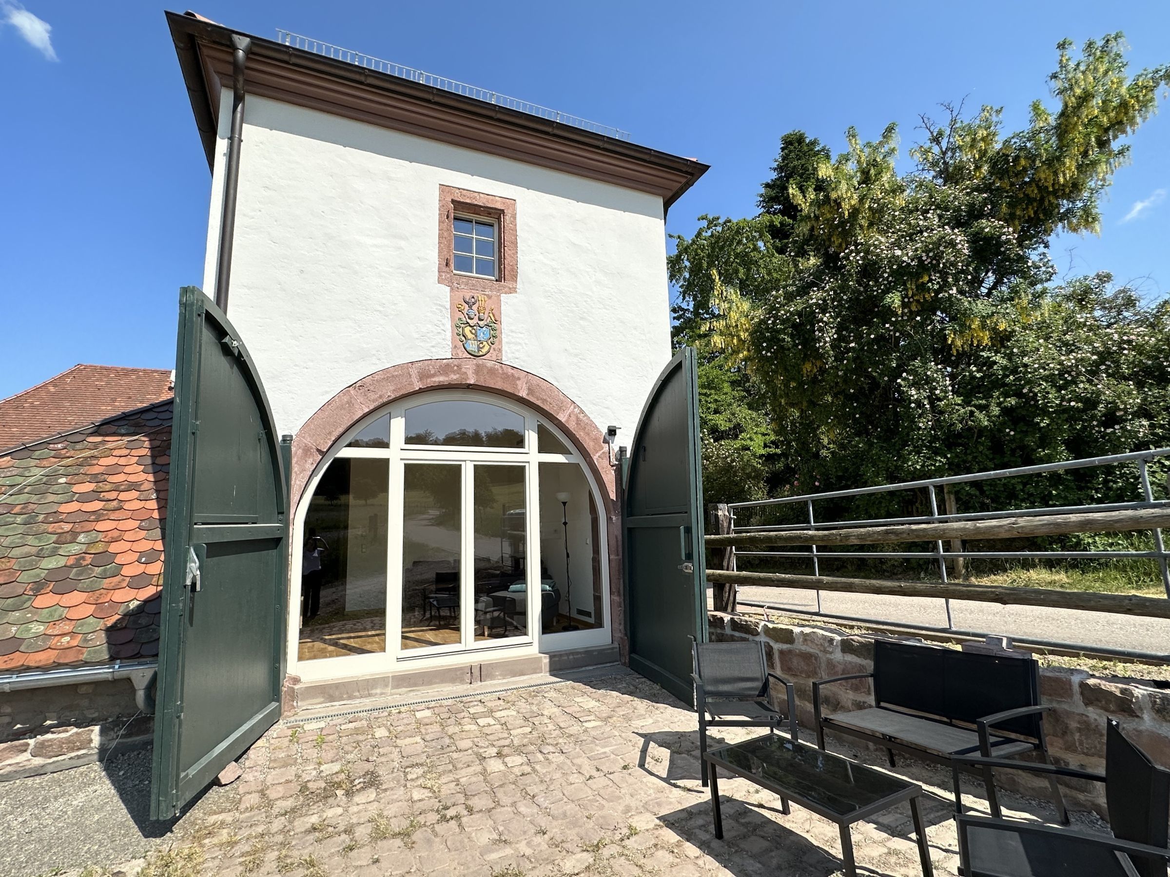 En bygning med en hvid facade, et våbenskjold og en stor buegang.