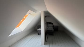 Ein Zimmer mit schrägem Dach und einem Oberlicht sowie einem Bett.