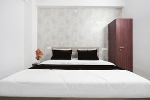 Un dormitorio moderno con una cama grande, dos almohadas negras, un armario de madera y una pared con textura.