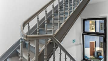 A staircase with a handrail and balusters, leading to a landing with a window.