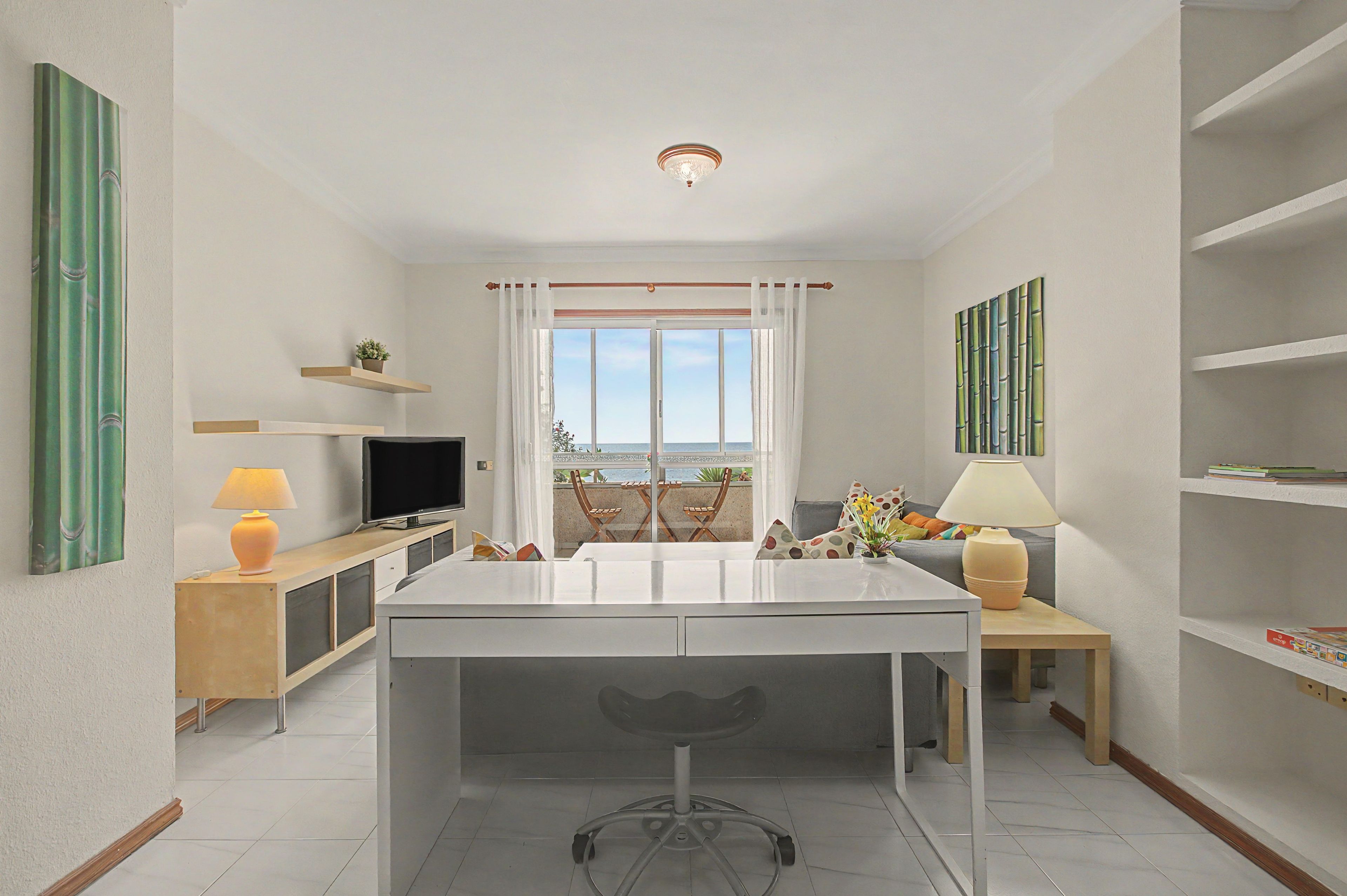 Et moderne køkken med en central ø, et spiseområde med bord og stole, et fjernsyn og havudsigt fra vinduet.