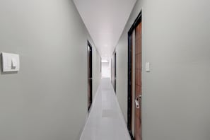 Passadís estret i ben il·luminat, amb un interruptor a l'esquerra i una porta amb mànec a la dreta.
