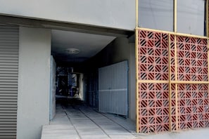Un passadís amb una reixa de metall i una porta blava, que condueix a una zona més fosca.