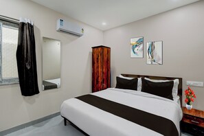 A hotel room with a bed, a mirror, an air conditioning unit, and two abstract paintings on the wall. - Townhouse Chaitanyapuri Metro Station (Hyderabad)