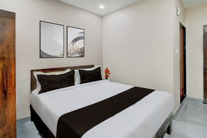 A hotel room with a bed, two wall-mounted artworks, and a wooden door. - Townhouse Chaitanyapuri Metro Station (Hyderabad)