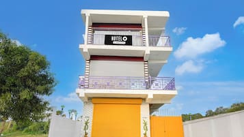 Un hôtel à plusieurs étages, avec une enseigne, une porte de garage jaune et un mur blanc sur lequel est inscrit le mot « Bienvenue ».