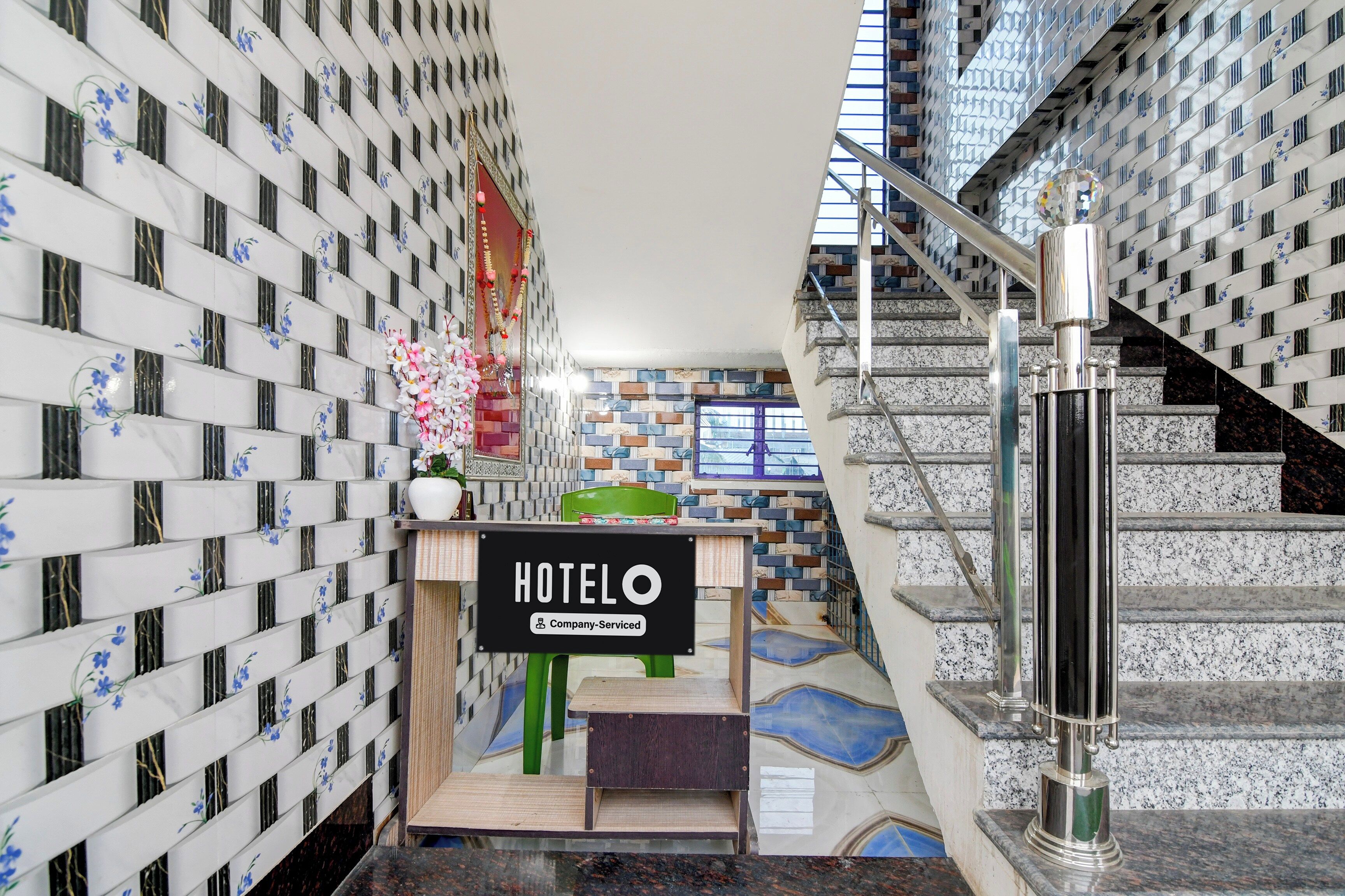 Un hall d’hôtel avec un escalier, un comptoir d’accueil et un panneau indiquant qu’il s’agit d’un hôtel géré par une entreprise.