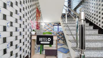 Un hall d’hôtel avec un escalier, un comptoir d’accueil et un panneau indiquant qu’il s’agit d’un hôtel géré par une entreprise.
