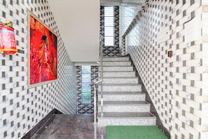 A staircase with a patterned wall design, a fire extinguisher, and a framed artwork.