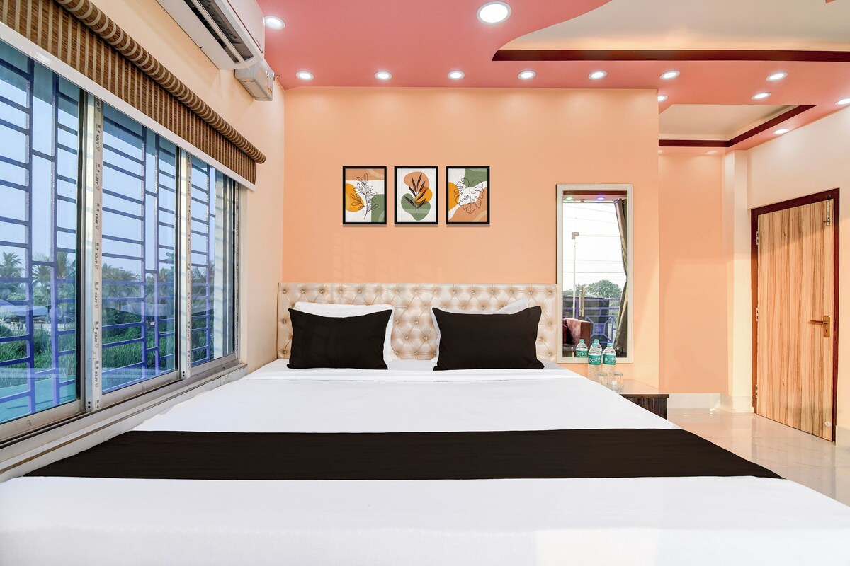 Une chambre d’hôtel avec un grand lit, une fenêtre avec des stores, un plafond doté d’un éclairage encastré et une porte.