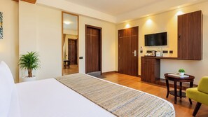 A hotel room with a bed, a small table, a chair, a TV, and a wardrobe.