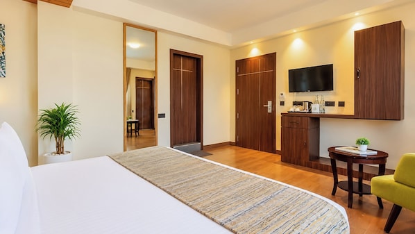 A hotel room with a bed, a small table, a chair, a TV, and a wardrobe.
