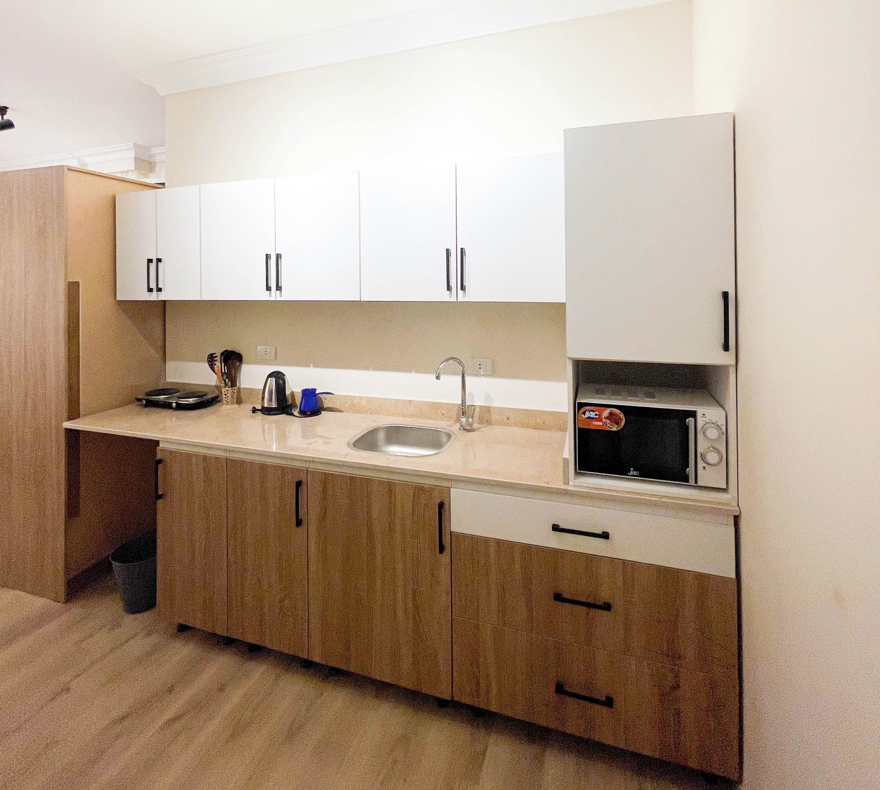 A kitchen with white cabinets, a sink, a microwave, and a coffee maker.