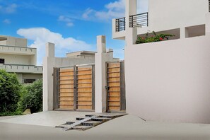 A modern building with a white facade, a gated entrance, and a small outdoor area with steps leading to a door.