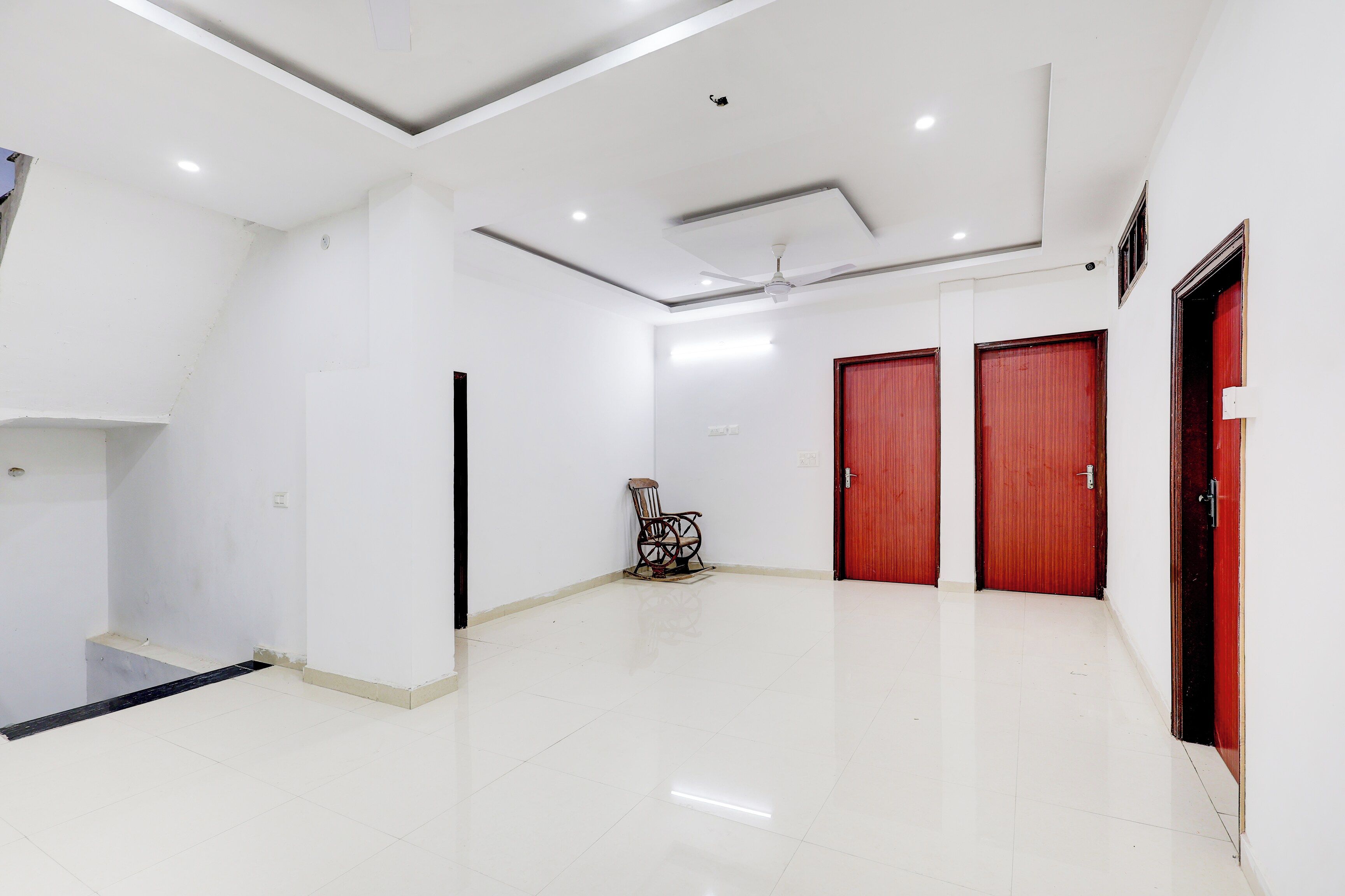 A spacious, well-lit room with white walls, a tiled floor, and a ceiling fan.