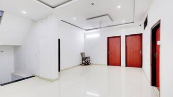 A spacious, well-lit room with white walls, a tiled floor, and a ceiling fan.