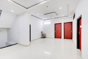 A spacious, well-lit room with white walls, a tiled floor, and a ceiling fan.