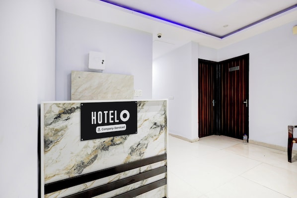 A hotel reception area with a marble reception desk, a security camera, and a closed door.