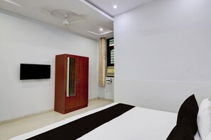 A bedroom with a bed, a wardrobe, a television, and a ceiling fan.