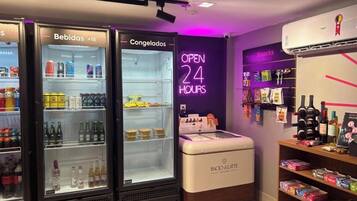 A 24-hour convenience store with refrigerated beverage and snack sections, a small ice cream display, and a wine and spirits shelf.