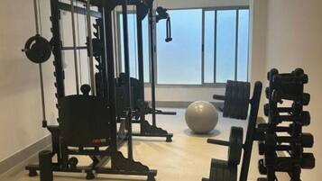 A gym with exercise equipment, a large window, and a view of the sky.