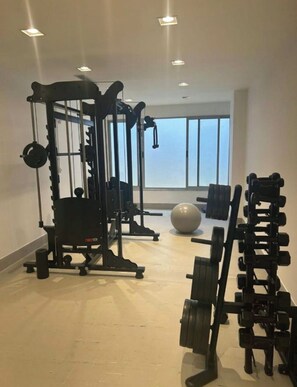 A gym with exercise equipment, a large window, and a view of the sky. - New Listing (Niterói)