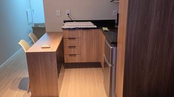 A compact kitchen with wooden cabinets, a countertop, and a built-in refrigerator.