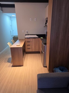 A compact kitchen with wooden cabinets, a countertop, and a built-in refrigerator.