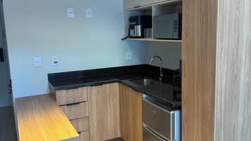 A modern kitchen with wooden cabinets, a stainless steel refrigerator, and a black countertop.